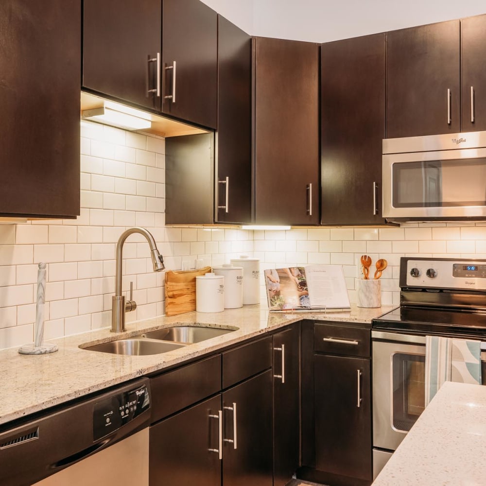 Subway tile backsplash and espresso wood cabinetry in a model apartment's kitchen at Lakeshore Pearl in Austin, Texas