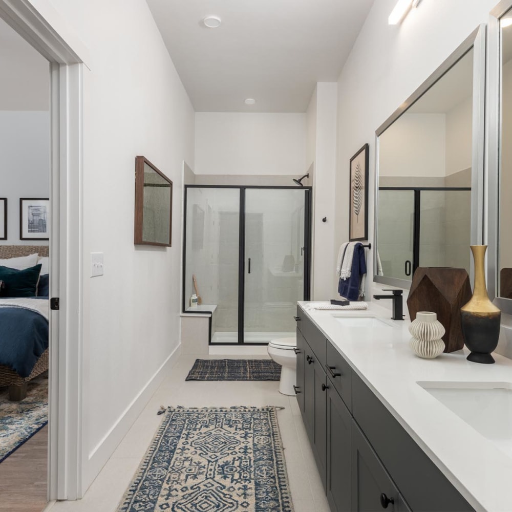 Dual sinks and a glass-enclosed shower in the primary bathroom of a model home at 4600 Ross in Dallas, Texas