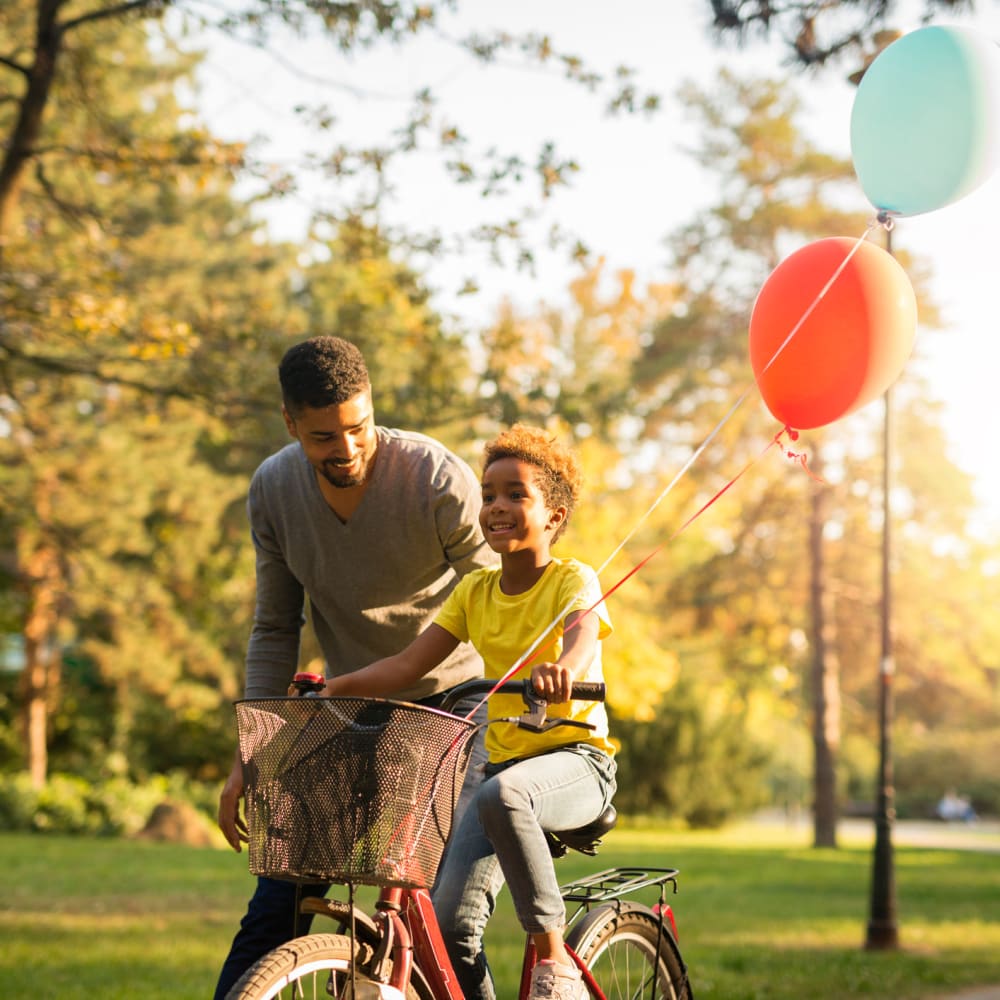 Father teaching his child how to ride a bike at Oaks Minnehaha Longfellow in Minneapolis, Minnesota