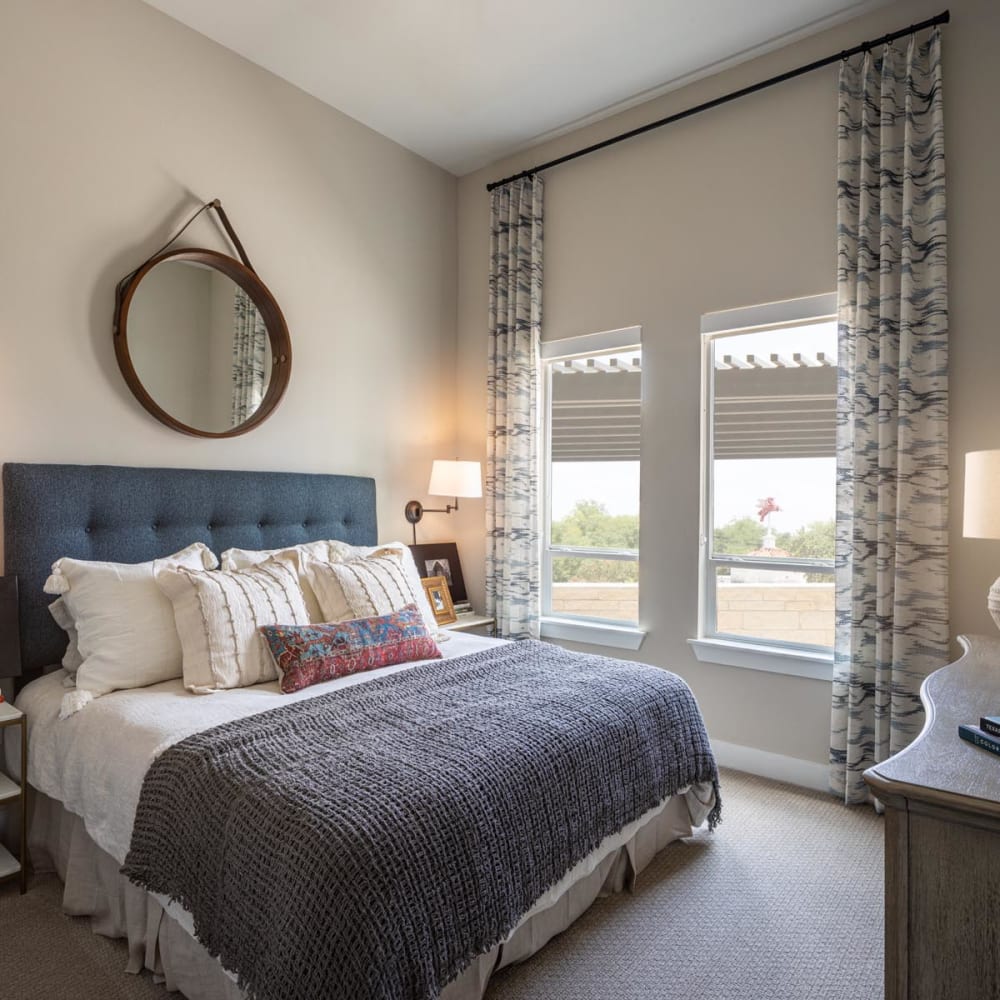 Well-furnished model apartment's bedroom with large bay windows at Magnolia Heights in San Antonio, Texas