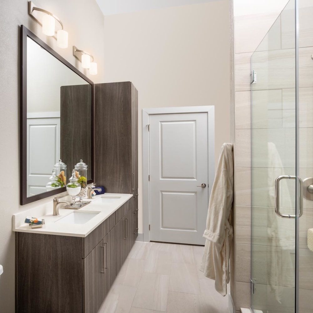 Large vanity mirror and a stand-up shower in a model home's bathroom at Magnolia Heights in San Antonio, Texas