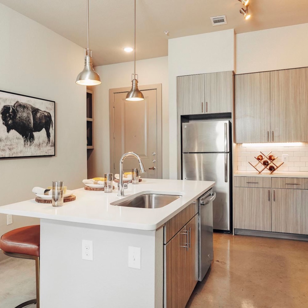 Model home's kitchen with quartz countertops and an island at The Guthrie in Austin, Texas