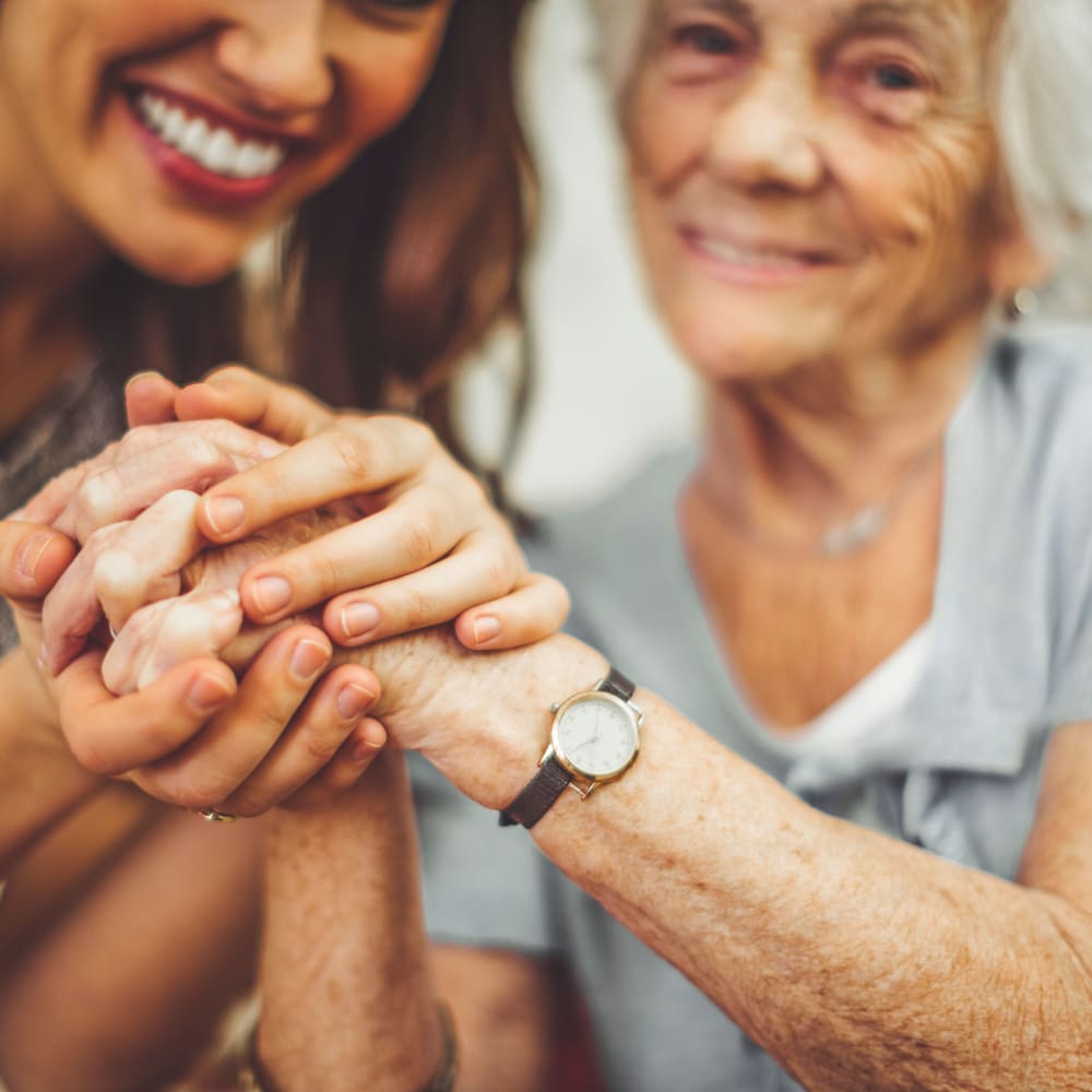 A caregiver and a resident holding hands at Inspired Living Delray Beach in Delray Beach, Florida