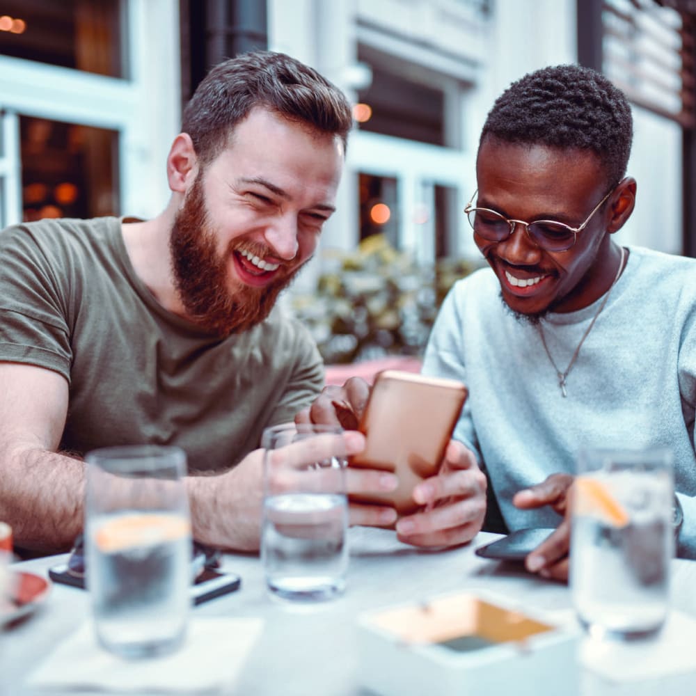 Couple outside sharing photos on their phones while waiting for their meal at a restaurant near Garland, Texas near Oaks 5th Street Crossing At City Center