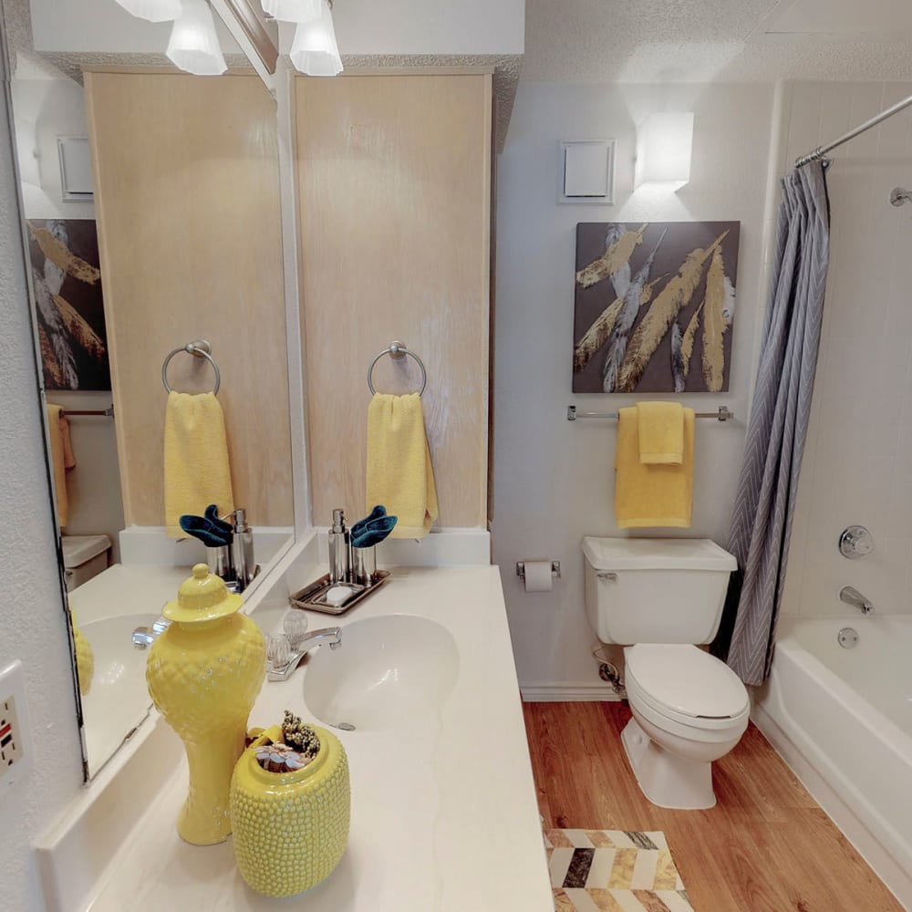 Large vanity mirror and wood-style flooring in a model apartment's bathroom at Oaks Hackberry Creek in Las Colinas, Texas