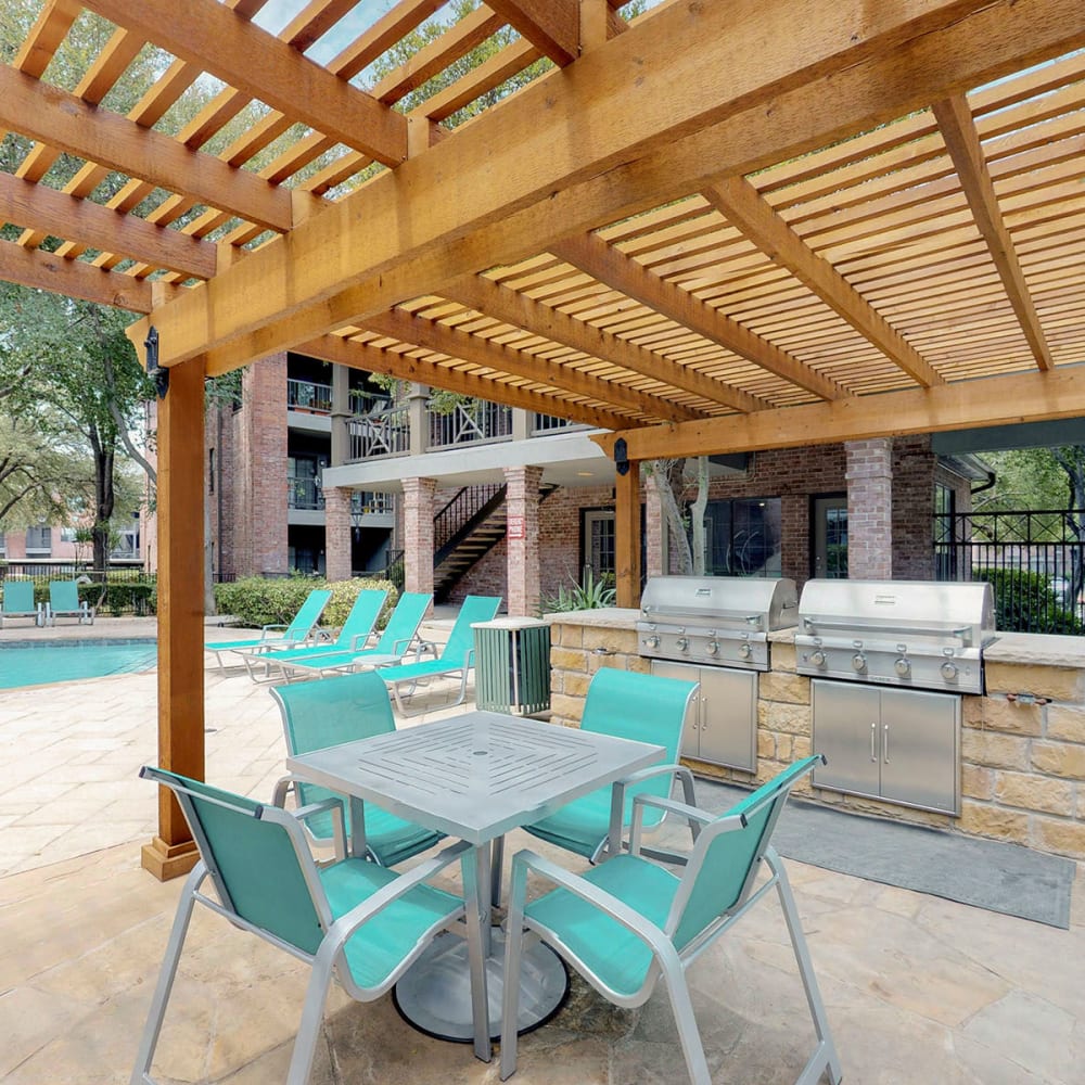 Pergola providing partial shade over a table and chairs near the barbecue area at Oaks Hackberry Creek in Las Colinas, Texas