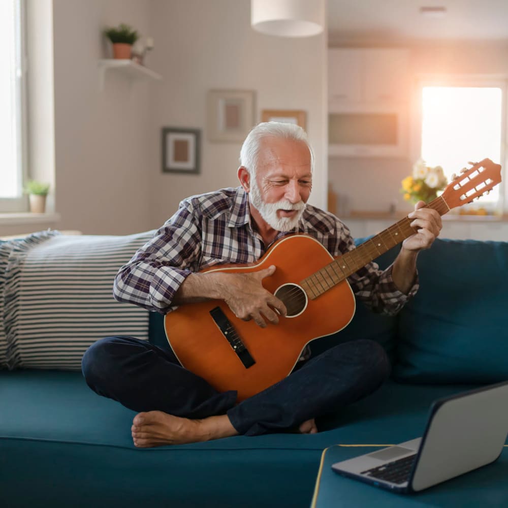 Resident practicing acoustic guitar in his apartment home at Oaks Hiawatha Station in Minneapolis, Minnesota