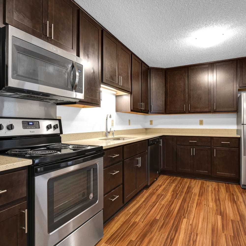 Hardwood flooring and dark wood cabinetry in a model townhome's kitchen at Oaks Lincoln Apartments & Townhomes in Edina, Minnesota