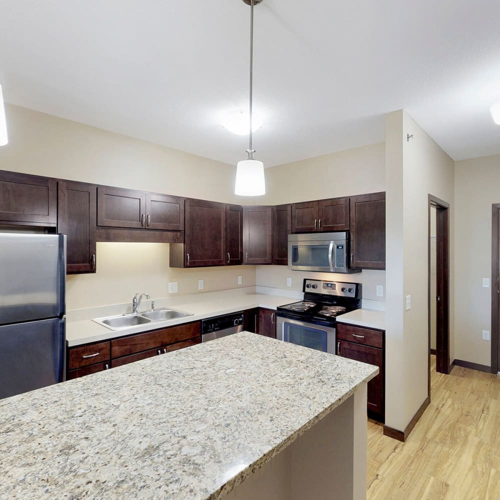 Spacious chef-inspired kitchen with an island and espresso wood cabinetry in a model apartment at Oaks Station Place in Minneapolis, Minnesota