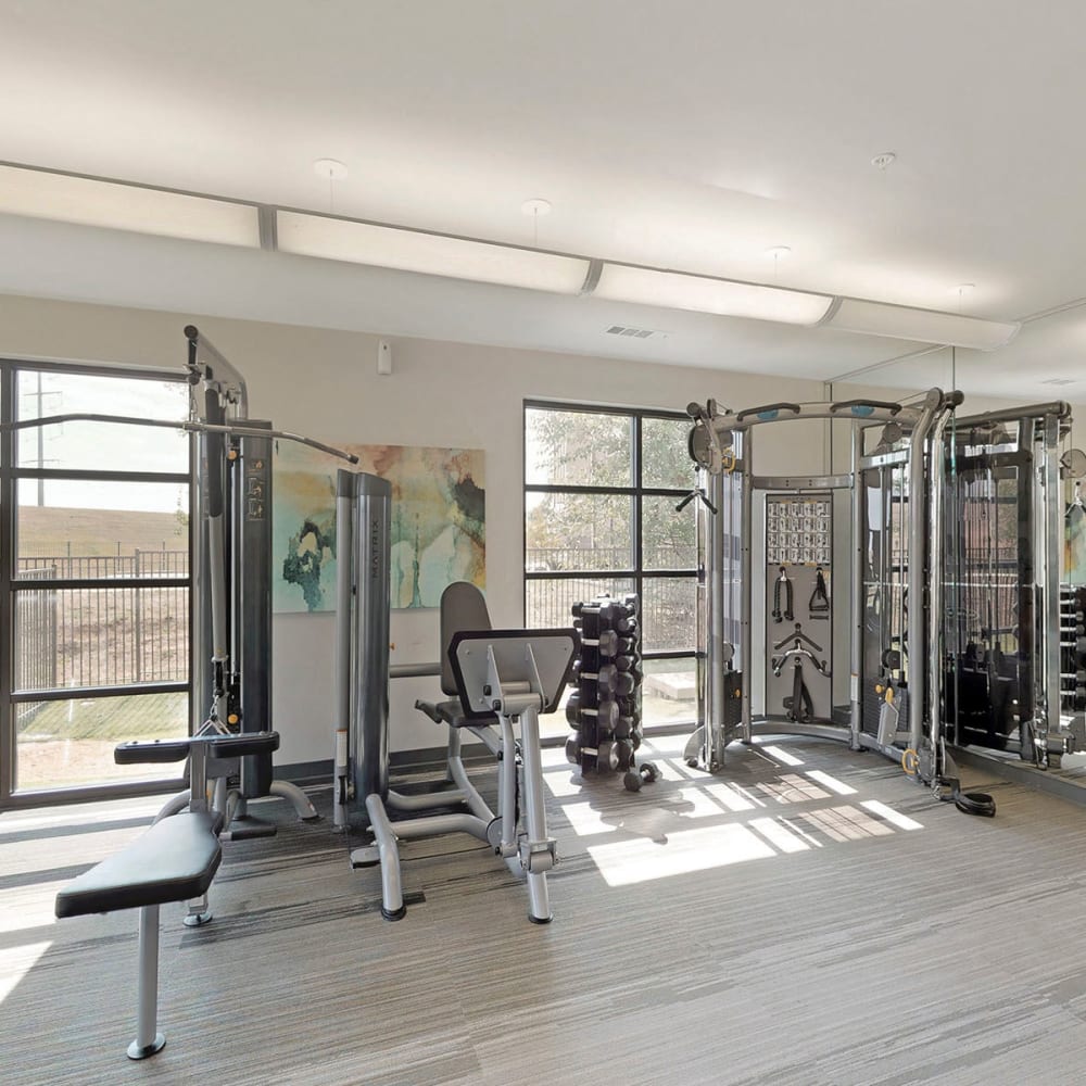 Free weights and exercise equipment in the onsite fitness center at Oaks Trinity in Dallas, Texas