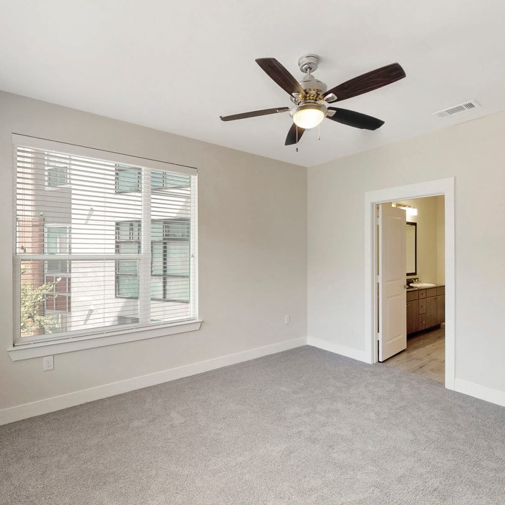 Plush carpeting and an en suite bathroom in the primary suite of a model home at Oaks Trinity in Dallas, Texas