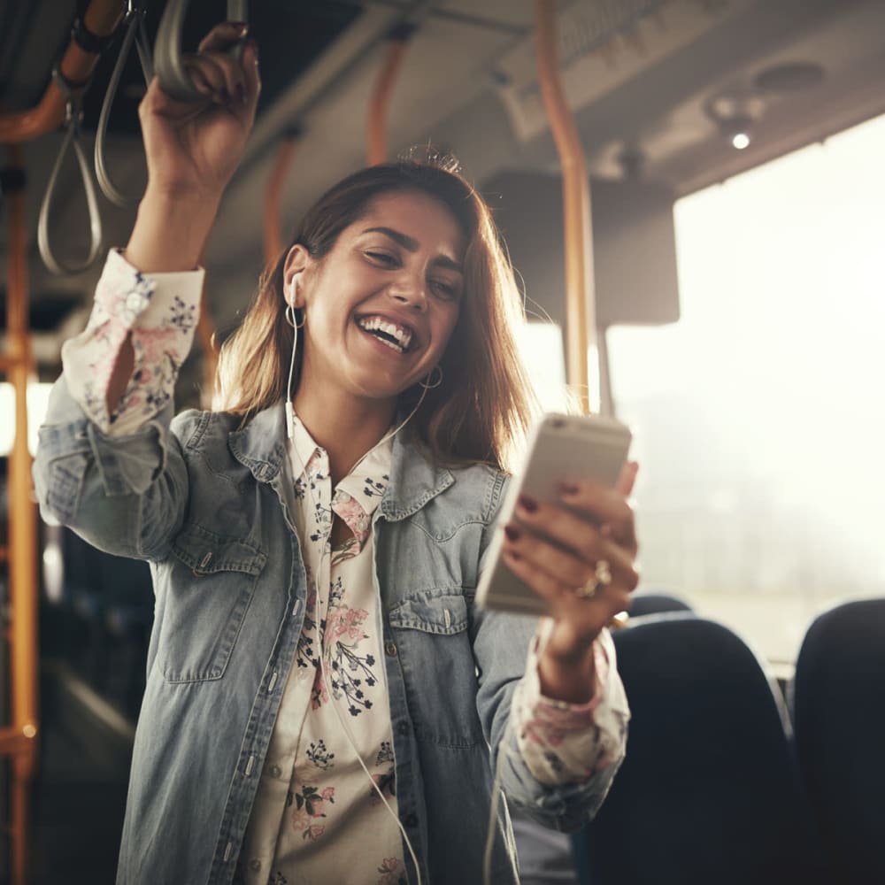 Resident laughing at something on her phone while riding the bus to work near Oaks Trinity in Dallas, Texas
