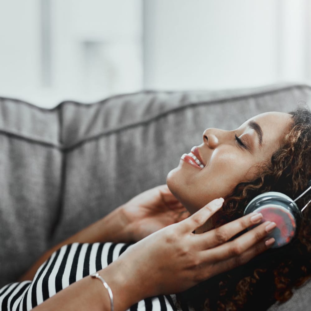 Resident listening to her favorite jams on headphones from the comfort of the couch in her apartment at Oaks Vernon in Edina, Minnesota