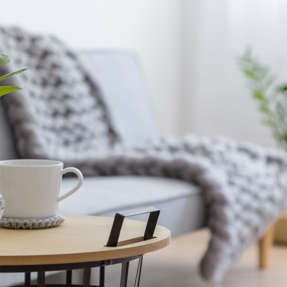 Cup of coffee on an end table next to a couch in a model home's living area at Oaks Vernon in Edina, Minnesota