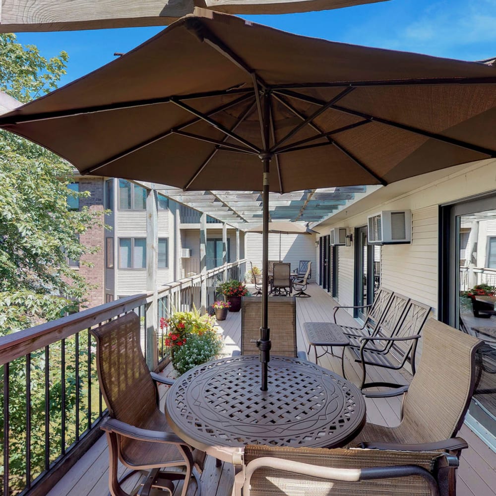 Shaded tables and chairs on the deck outside the resident clubhouse at Oaks Vernon in Edina, Minnesota