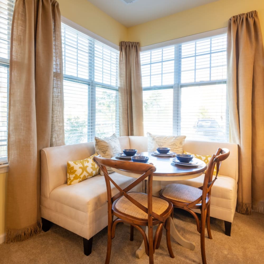Dining nook with a cute sectional couch surrounded by windows at The Reserve at White Oak in Garner, North Carolina