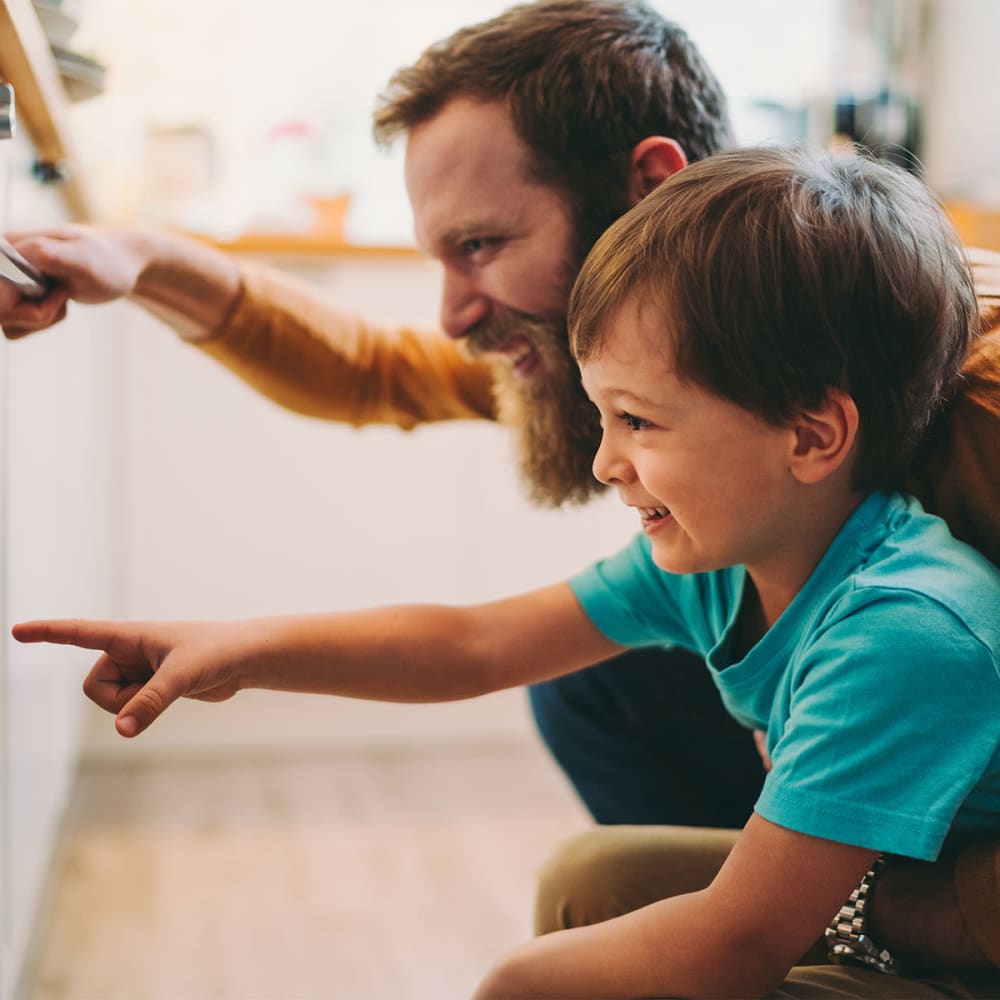 Father showing his young son the finer points of kitchen cabinetry in their new apartment at Mission Rock at Novato in Novato, California