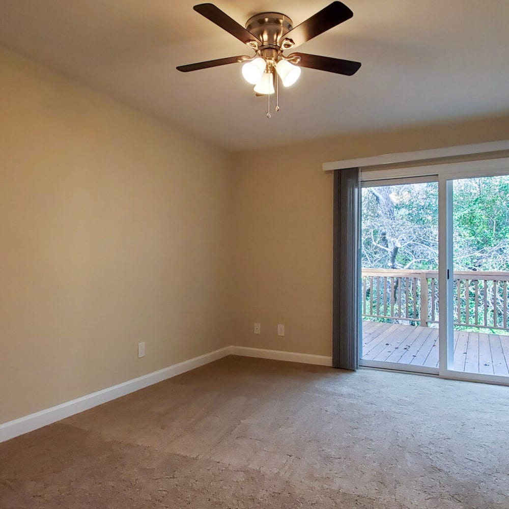 Living room with plush carpeting and a view of the large patio/balcony in a model home at Mission Rock at Marin in San Rafael, California