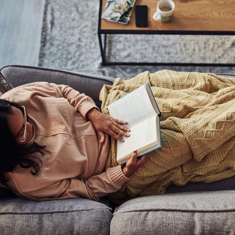 Resident relaxing with a good book on the couch in her new apartment at Mission Rock at Marin in San Rafael, California