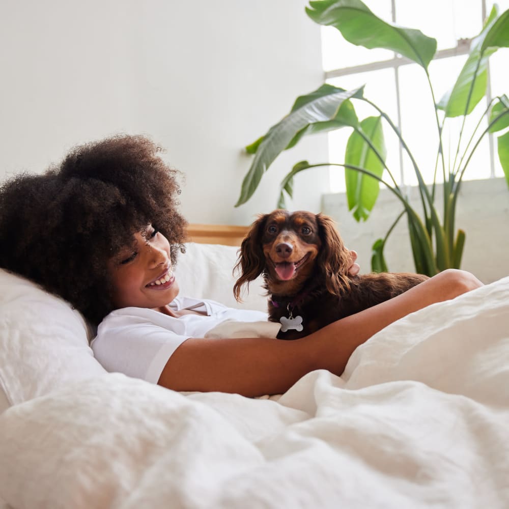 Resident relaxing in bed with her pup in their new home at Mission Rock at Sonoma in Sonoma, California