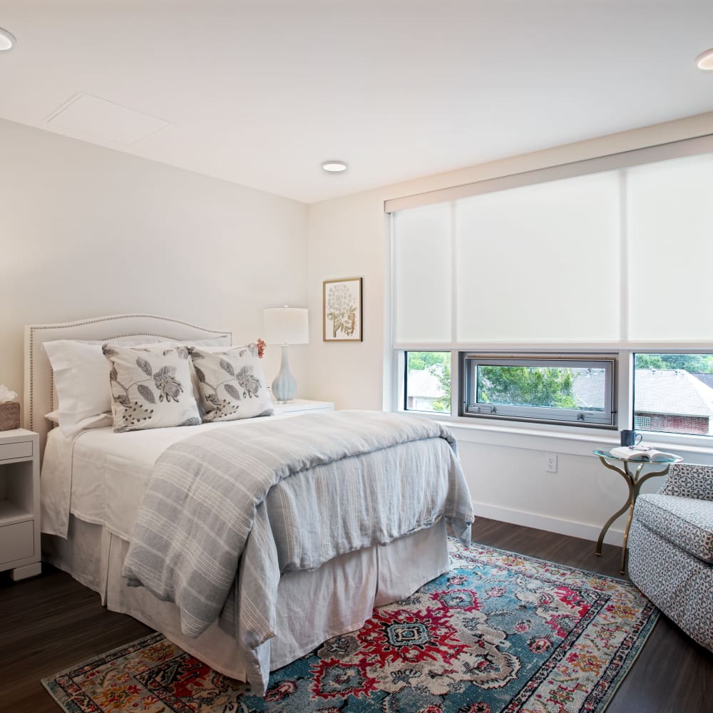 Example resident bedroom with a rug and a bed at The Village of Southampton in Houston, Texas