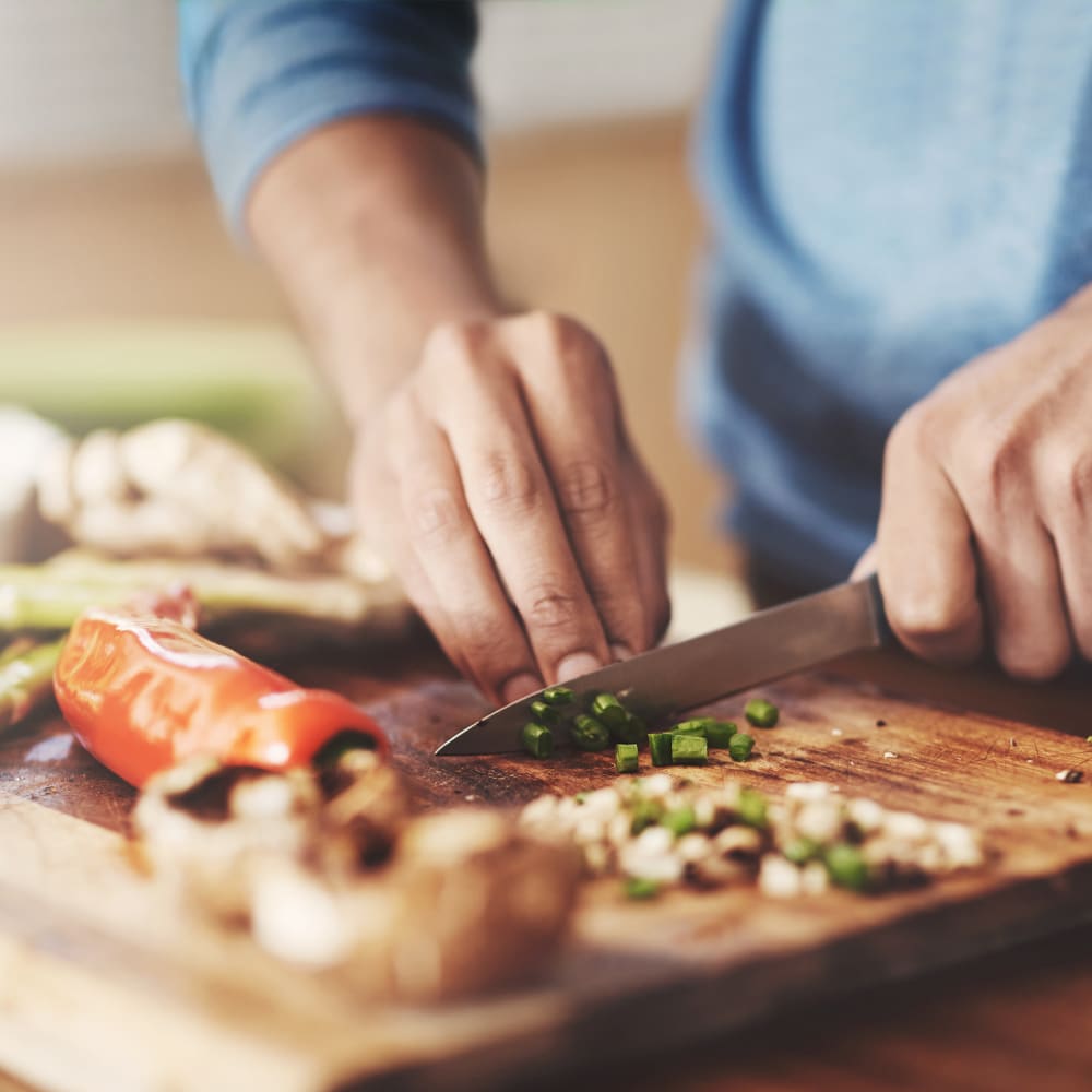 Resident dicing fresh vegetables for dinner in the kitchen of his apartment at Farmstead at Lia Lane in Santa Rosa, California