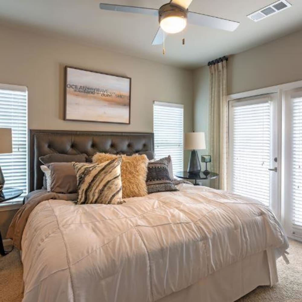 A king sized bed in a model bedroom with doors to the balcony at Lullwater at Blair Stone in Tallahassee, Florida