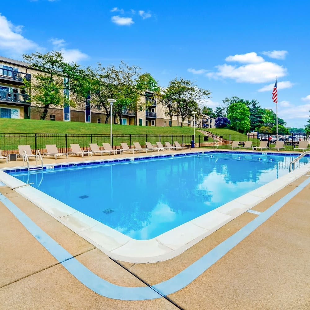 Swimming pool surrounded by lounge chairs at Squires Manor Apartment Homes in South Park, Pennsylvania