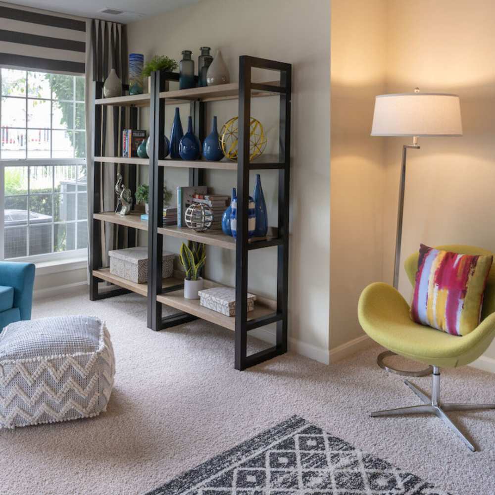 A cozy room featuring a chair, ottoman, and filled bookshelves, creating a warm reading space at The Elms at Oakton in Fairfax, Virginia