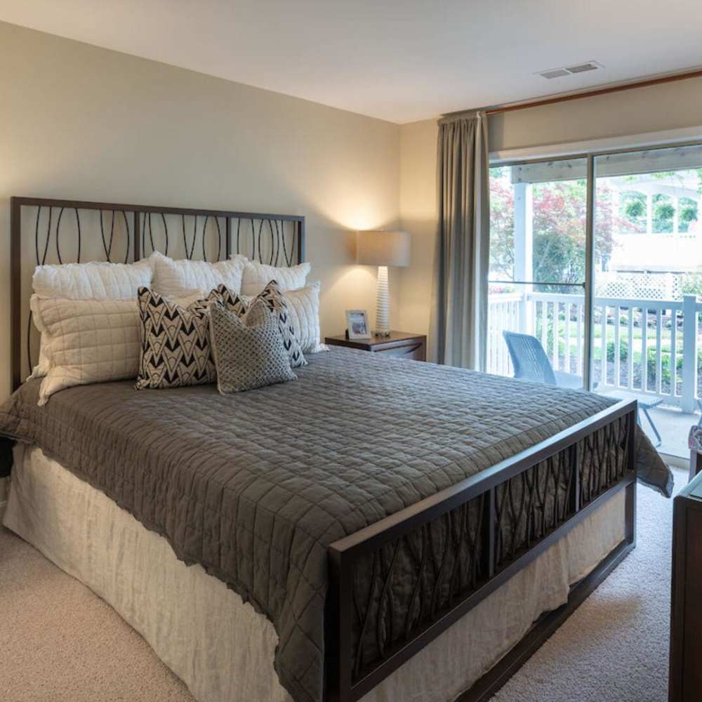 Spacious bedroom with large comfortable bed and patio sliding door at The Elms at Oakton in Fairfax, Virginia