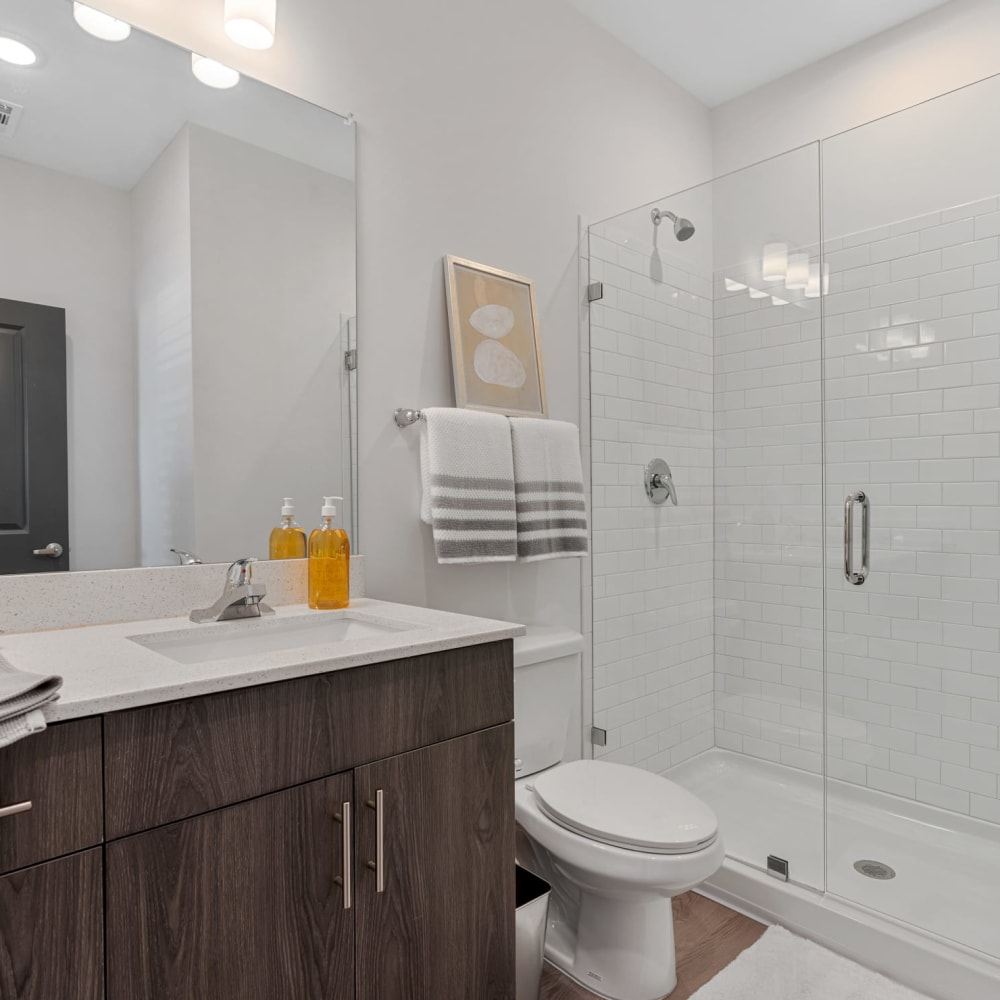 An apartment bathroom with glass shower doors at The Station at Clift Farm in Madison, Alabama