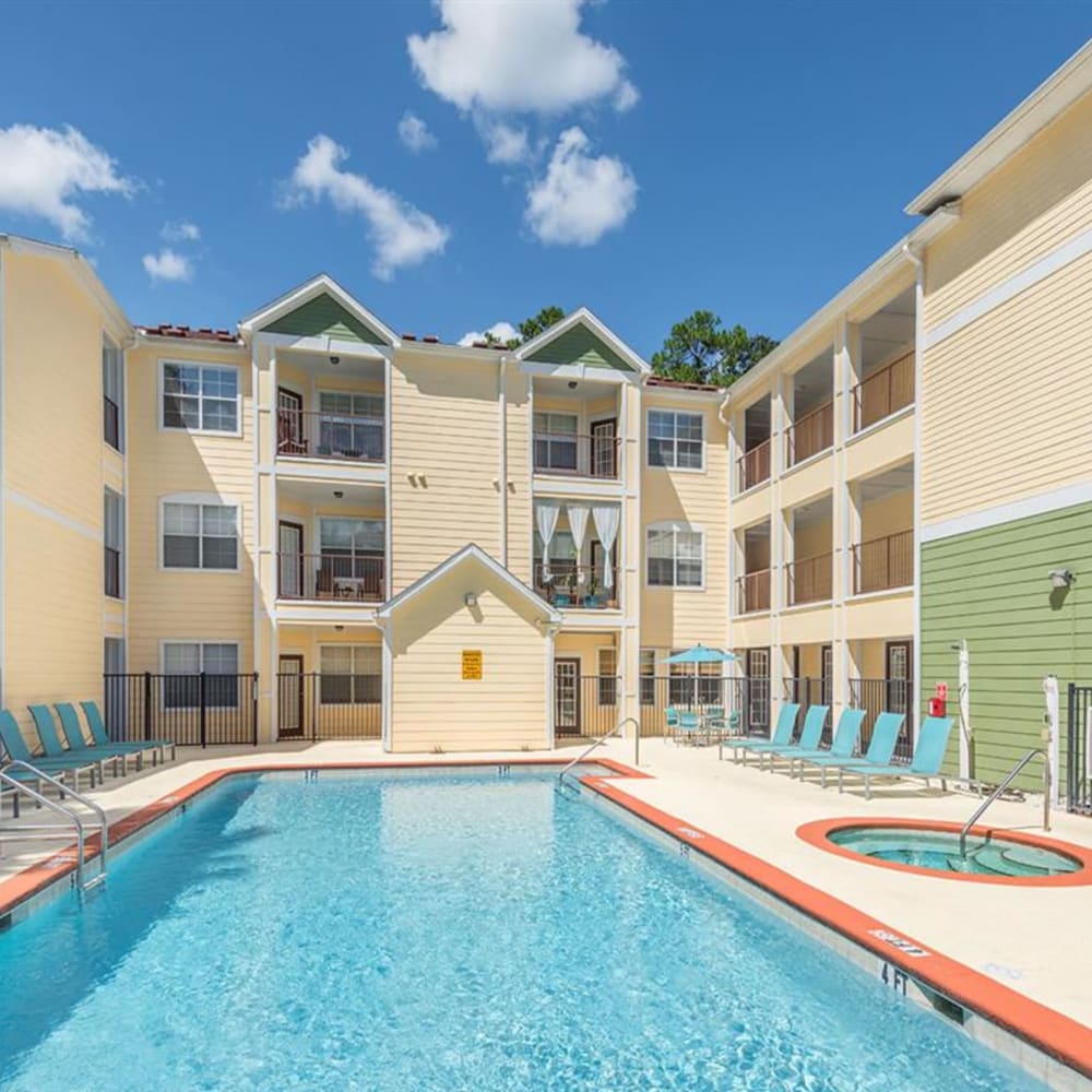 Community swimming pool with apartments in the background at Evergreens at Mahan in Tallahassee, Florida