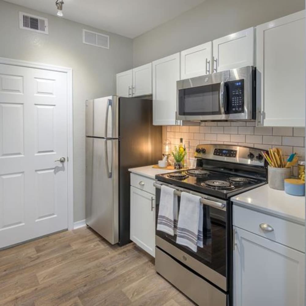 Wood floors and stainless steel appliances in an apartment kitchen at Evergreens at Mahan in Tallahassee, Florida