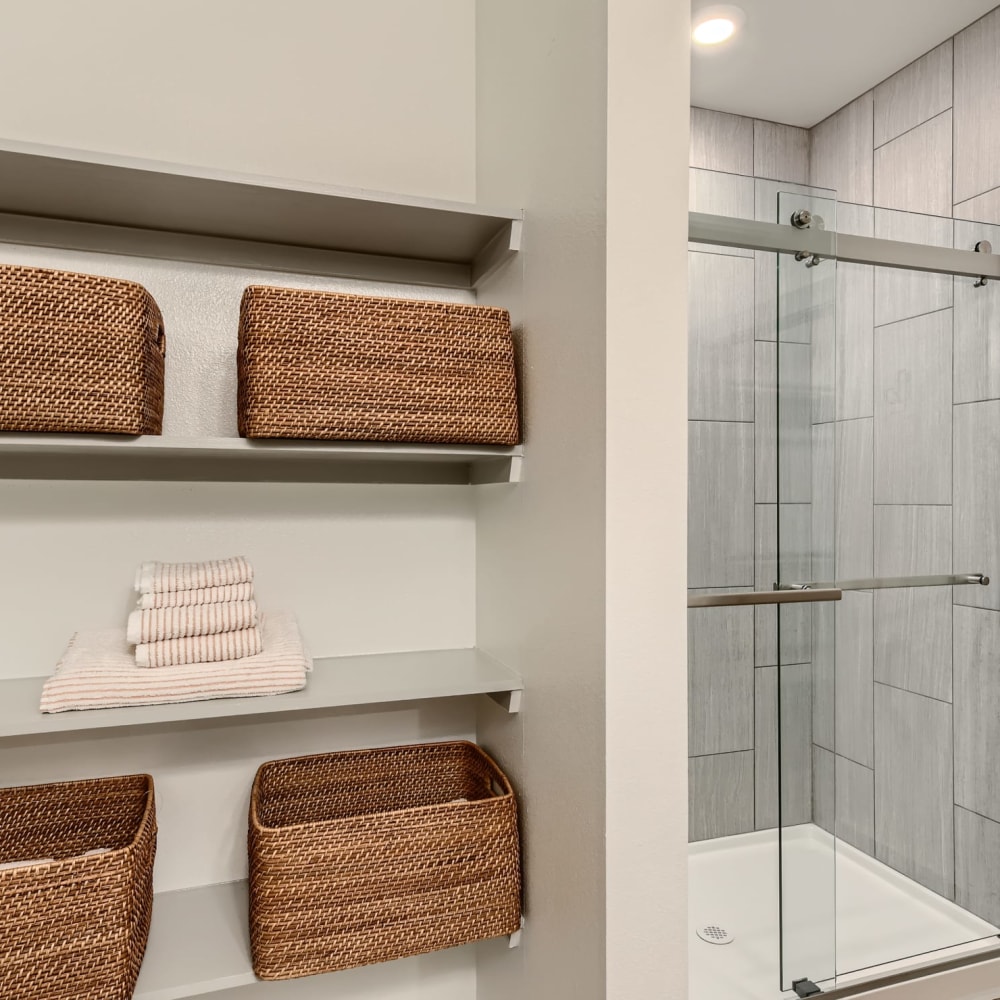 Built-in shelving next to the glass door shower in an apartment at Cypress McKinney Falls in Austin, Texas