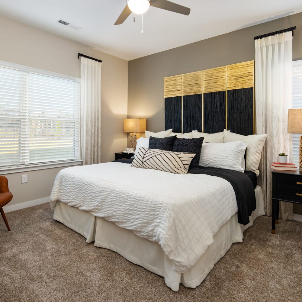 Plush carpeting and a large bed in the main bedroom of an apartment at The Alexandria in Madison, Alabama