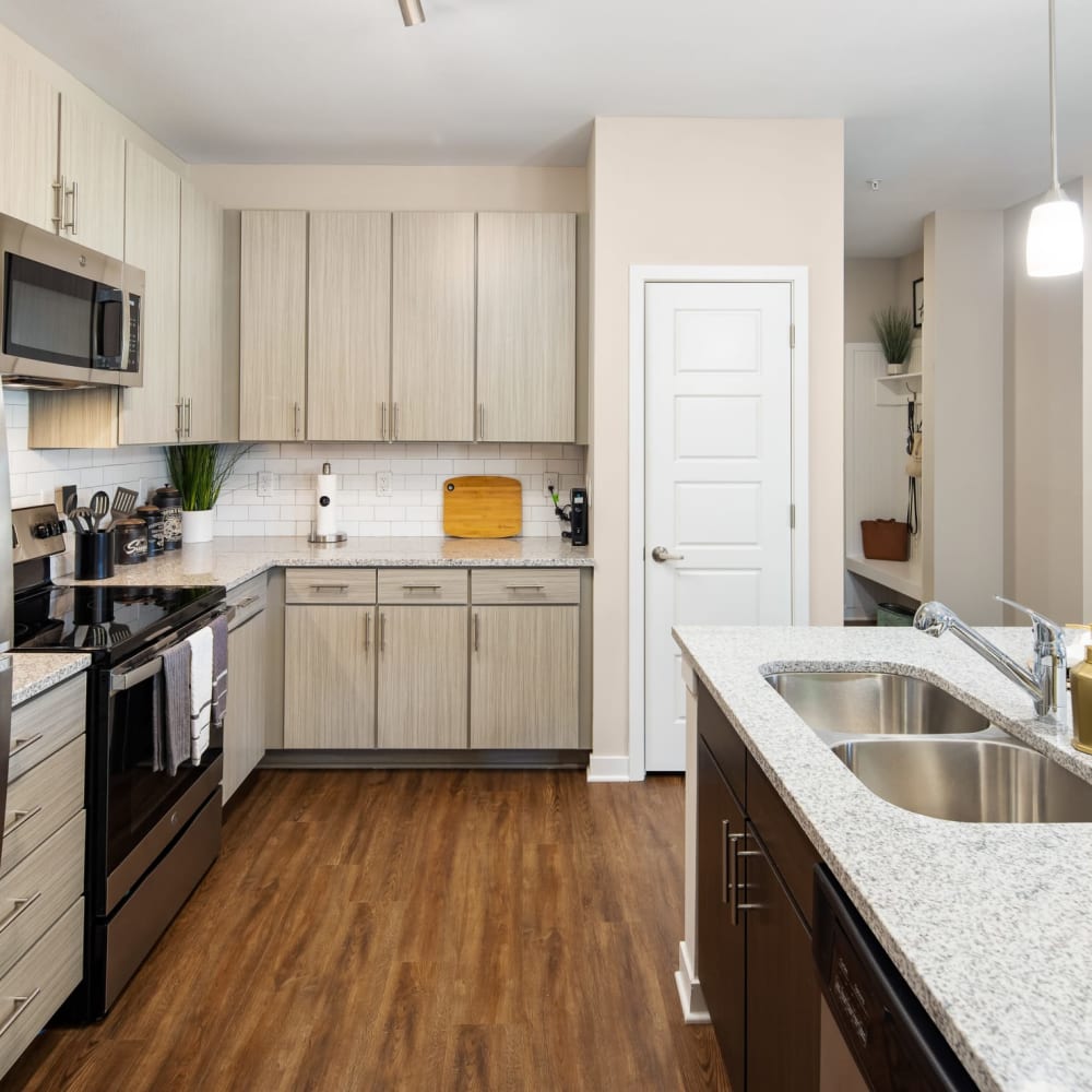 Stainless steel appliances and wood flooring in an apartment kitchen at The Alexandria in Madison, Alabama