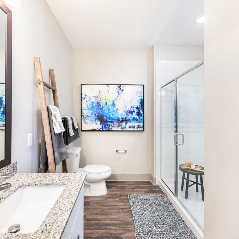 Wood flooring and a glass doored shower in an apartment bathroom at The Highland in Augusta, Georgia