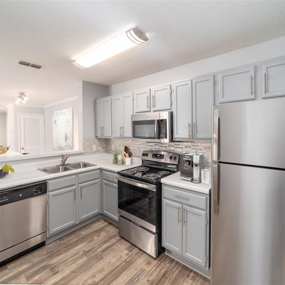 Wood flooring and stainless steel appliances in an apartment kitchen at Astoria in Mobile, Alabama
