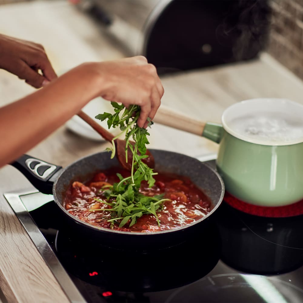 A woman's hands cooking a meal in her kitchen at Mode at Hyattsville in Hyattsville, Maryland