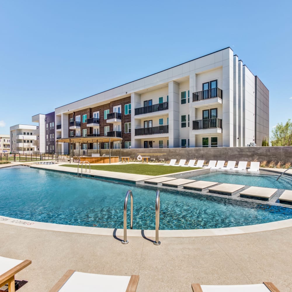 Swimming pool with pool-side seating at Mezzo Apartments in Aubrey, Texas