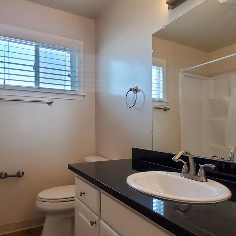 Granite countertop and a large vanity mirror in an apartment's bathroom at Mission Rock at Novato in Novato, California