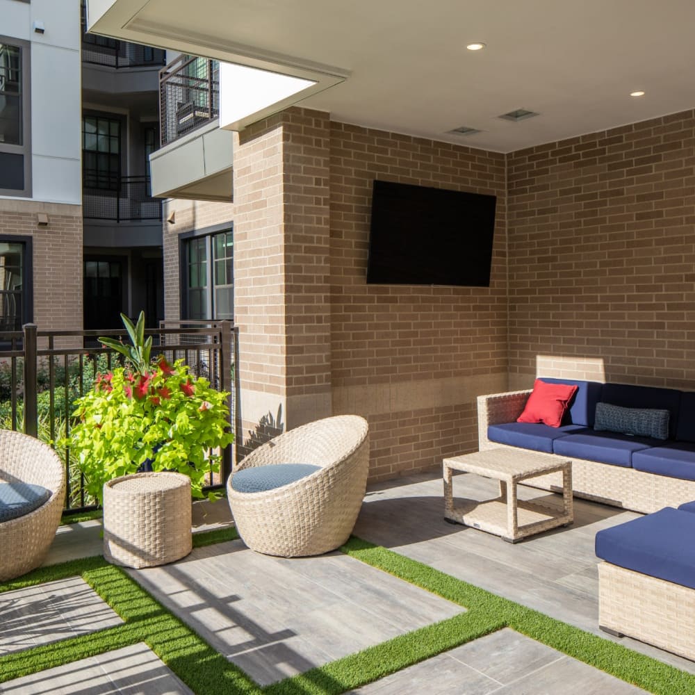 Outdoor resident seating area with modern patio furniture and large television at Bellrock Sawyer Yards in Houston, Texas