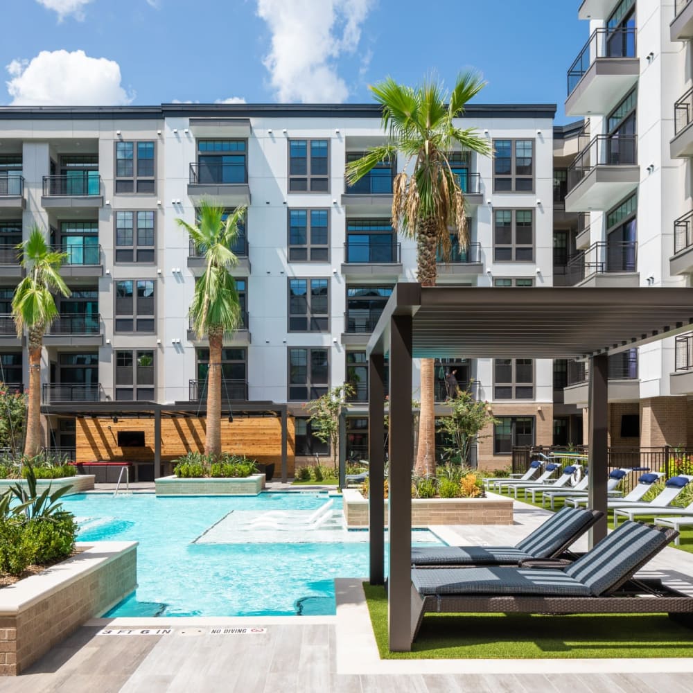 Community pool with covered lounge chairs at Bellrock Sawyer Yards in Houston, Texas