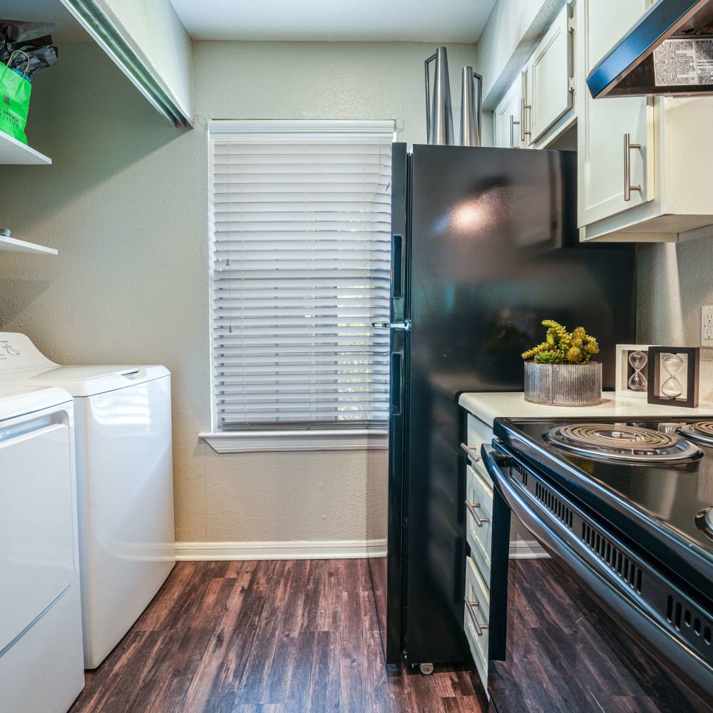 Kitchen and laundry area with wood-style flooring at The Madison on the Lake in Houston, Texas