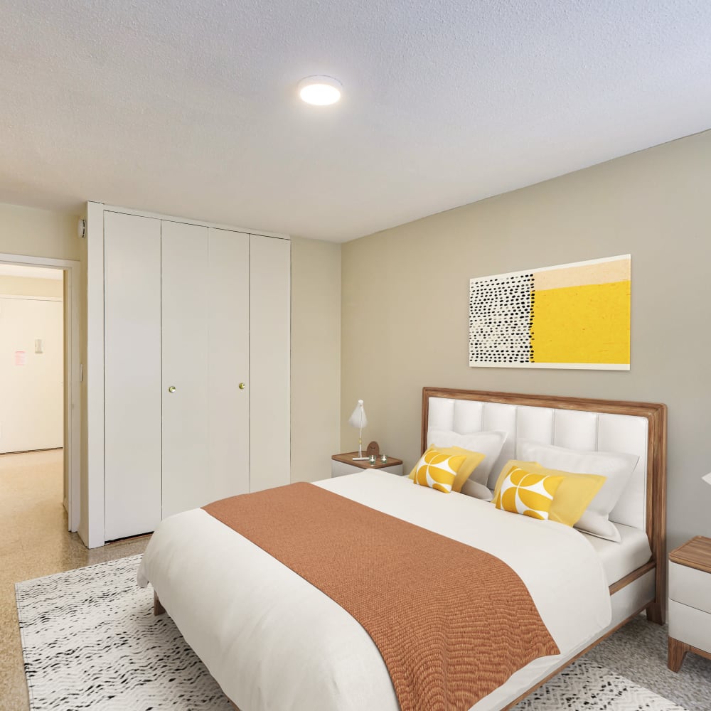 Model bedroom with orange accents and wall art at Tower West Apartments in New York, New York