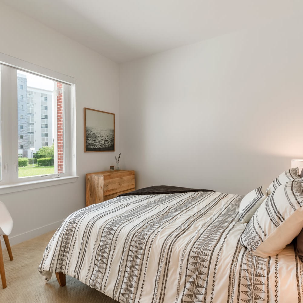 Model bedroom with bed looking towards window at Metro Green Court in Stamford, Connecticut