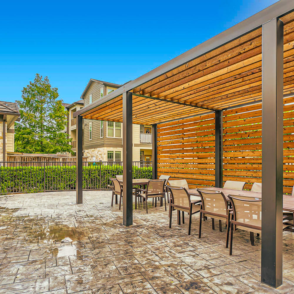Poolside table and chairs with covered shade area at Discovery at Kingwood in Kingwood, Texas