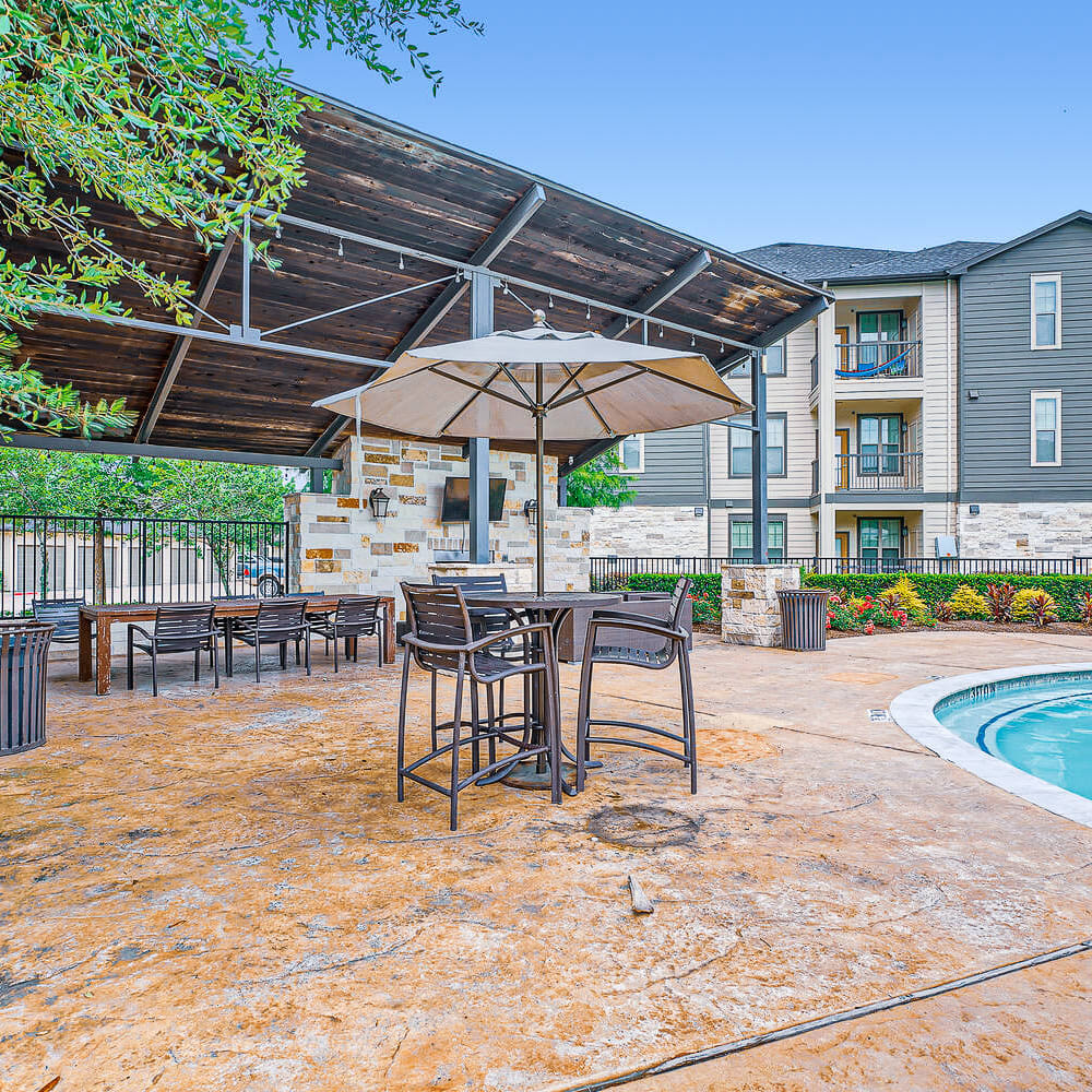 Poolside table and chairs with covered shade area at Discovery at Kingwood in Kingwood, Texas