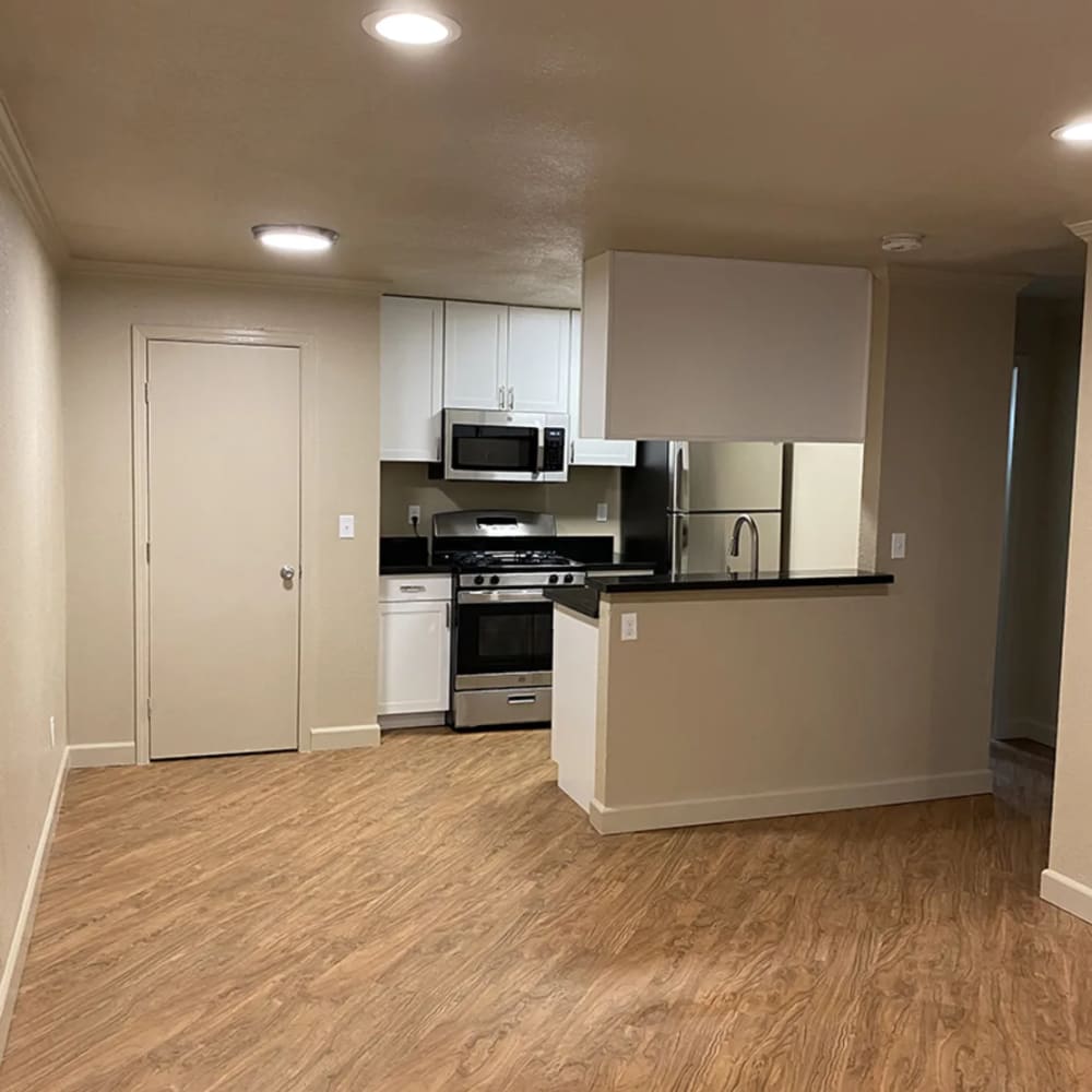 Open floor plan apartment kitchen and living area with wood-style flooring at Iron Horse Apartments in Stockton, California