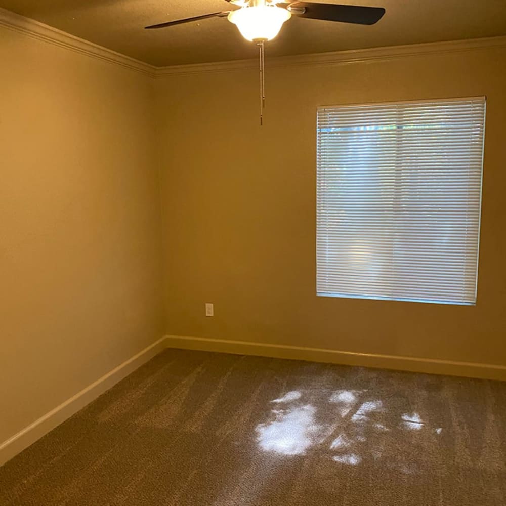 Bedroom with a ceiling fan and large window at Iron Horse Apartments in Stockton, California
